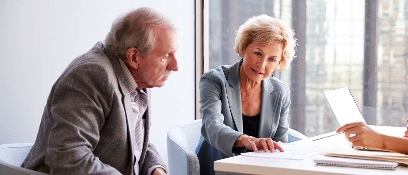 inheritance tax advisor giving information and help to an elderly couple looking for inheritance tax advice in an office.